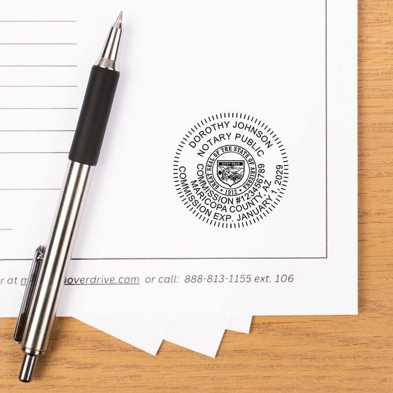 Arizona notary stamp impression on document with striped pen on wooden desk.