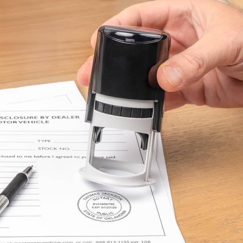 Hand pressing down on a round notary stamp, showing a labeled stamp impression size.    