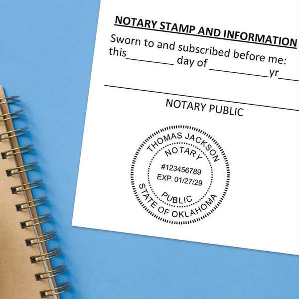 Stamped notary seal on a document next to a spiral notebook on a blue background.