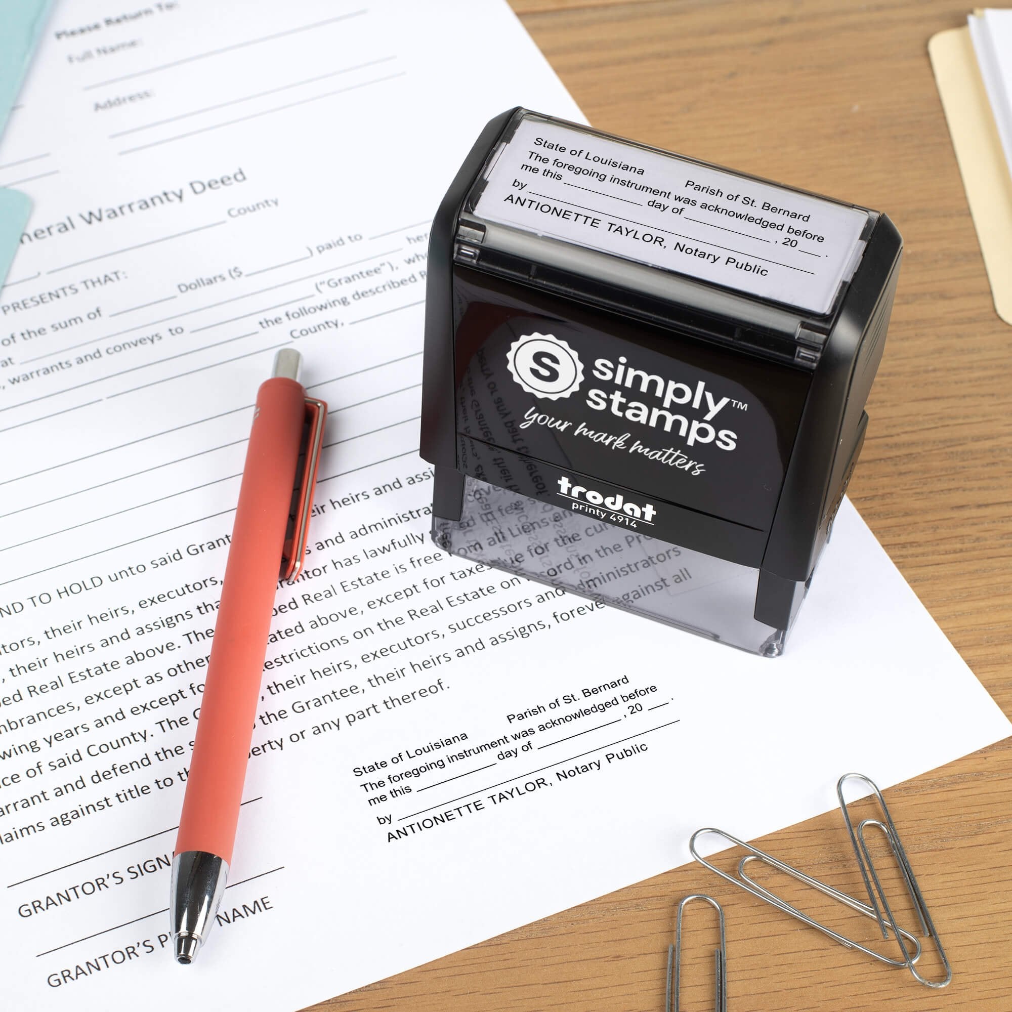 Louisiana notary self-inking stamp placed on a completed document beside a pen and paper clips, showing the acknowledgment impression in use.