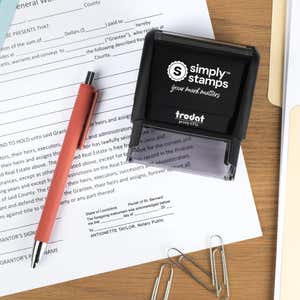 Top-down lifestyle photo of a Louisiana notary stamp on paperwork with a coral pen and office accessories nearby.