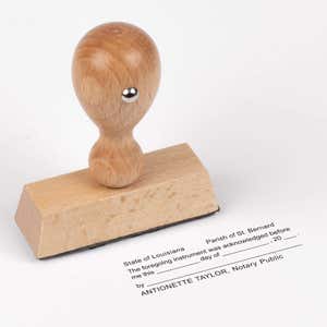 Traditional wood-handle Louisiana notary stamp displayed above its stamped acknowledgment impression.