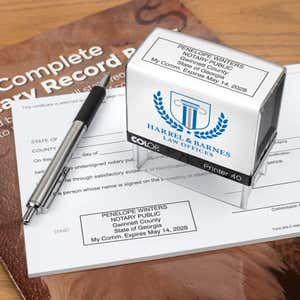 The Custom Georgia Notary Stamp on a document next to a pen and the stamp body